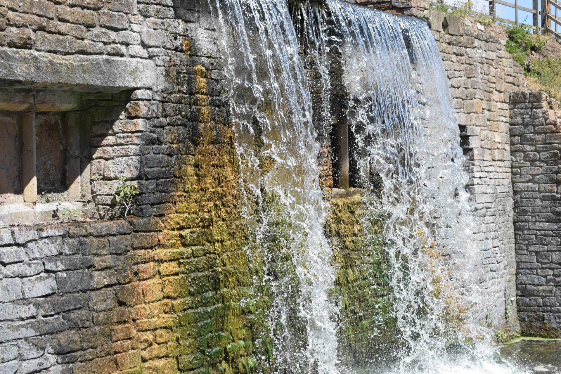 Waterfall cascading over an old stone wall