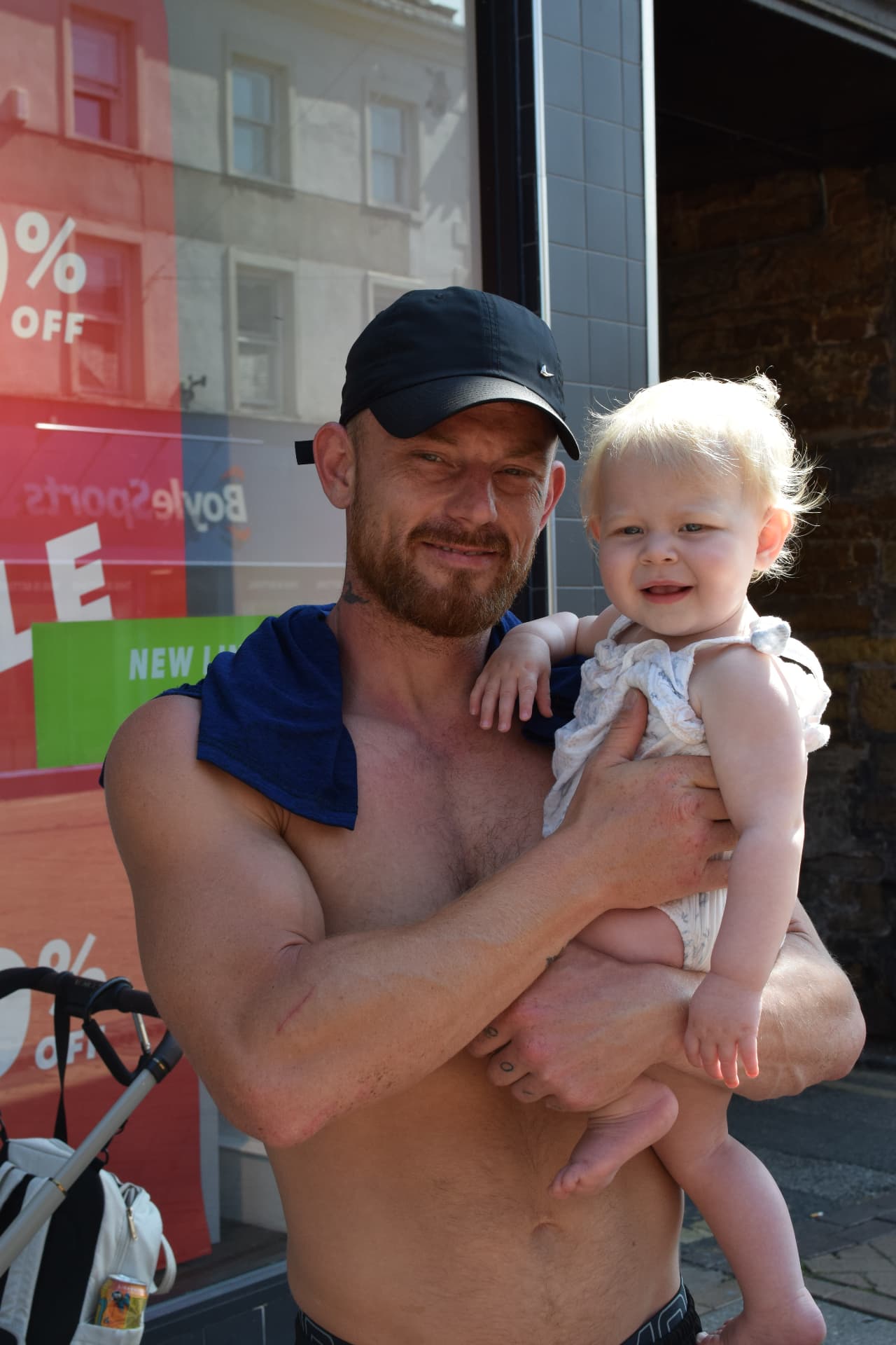Father holding his baby daughter on a sunny street